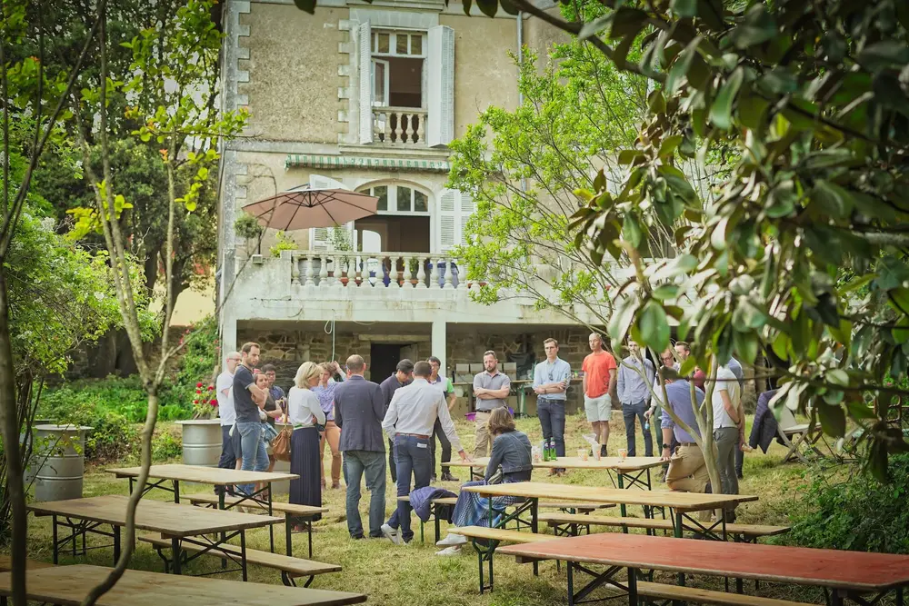 Collaborateurs réunis dans le jardin d'une maison bourgeoise lors d'un événement d'entreprise