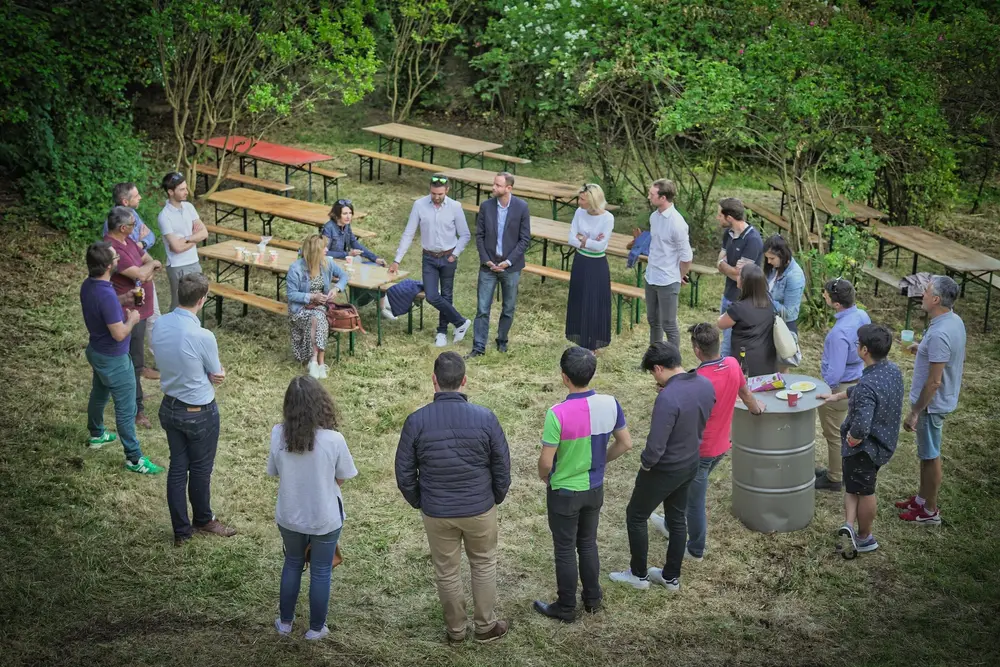 Une équipe discute en cercle dans un jardin pendant un événement professionnel