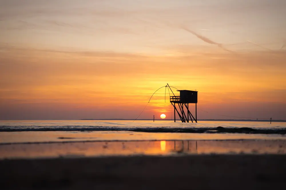Carrelet de pêche en silhouette au coucher du soleil sur la côte atlantique