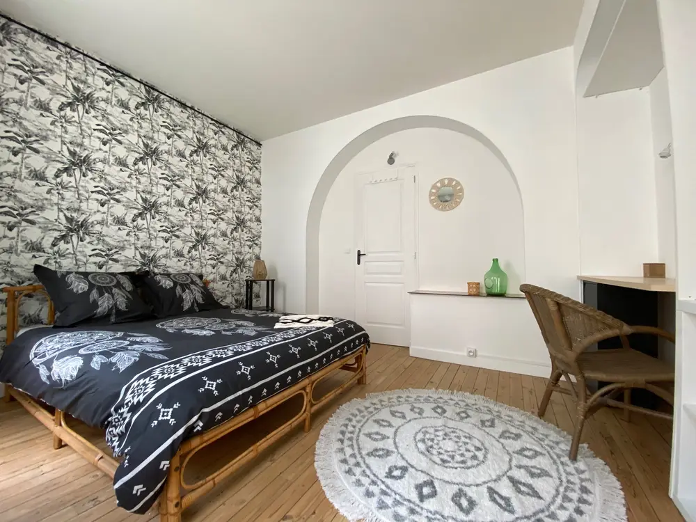 Chambre bohème avec papier peint tropical et lit en rotin dans un appartement nantais