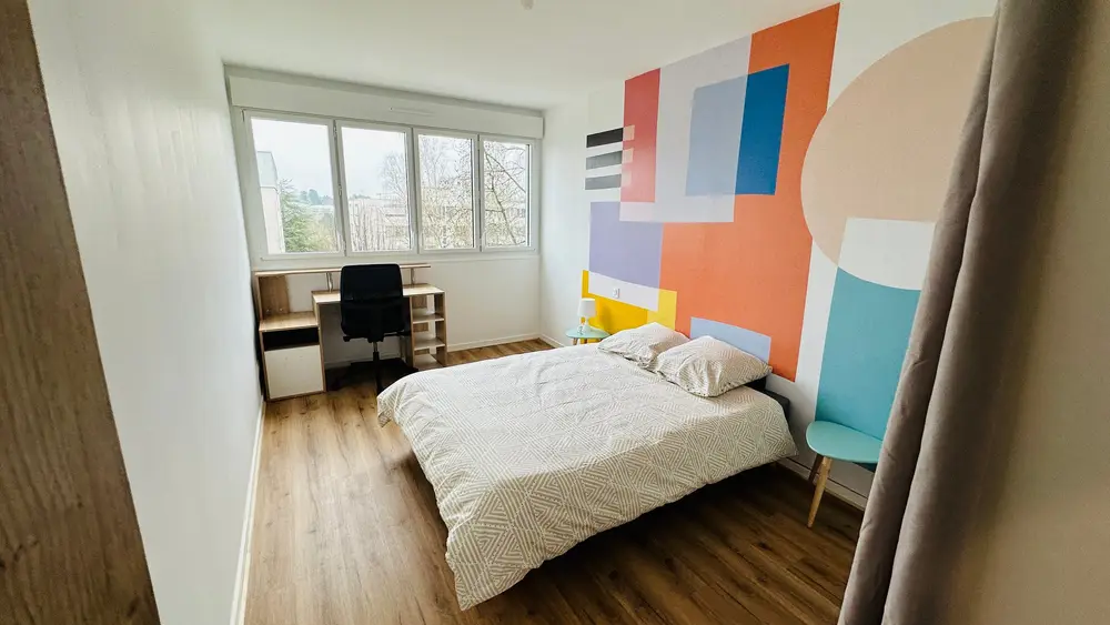 Chambre avec bureau et fresque murale colorée dans un appartement rénové