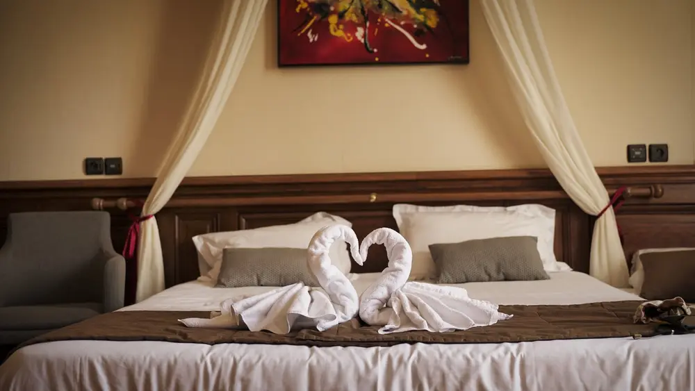 Chambre d'hôtel avec lit à baldaquin et serviettes pliées en forme de cygnes