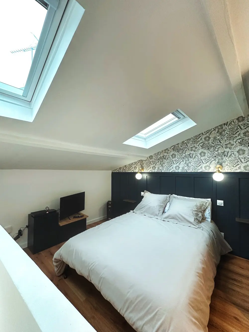 Chambre mansardée avec fenêtres de toit et tête de lit bleu nuit