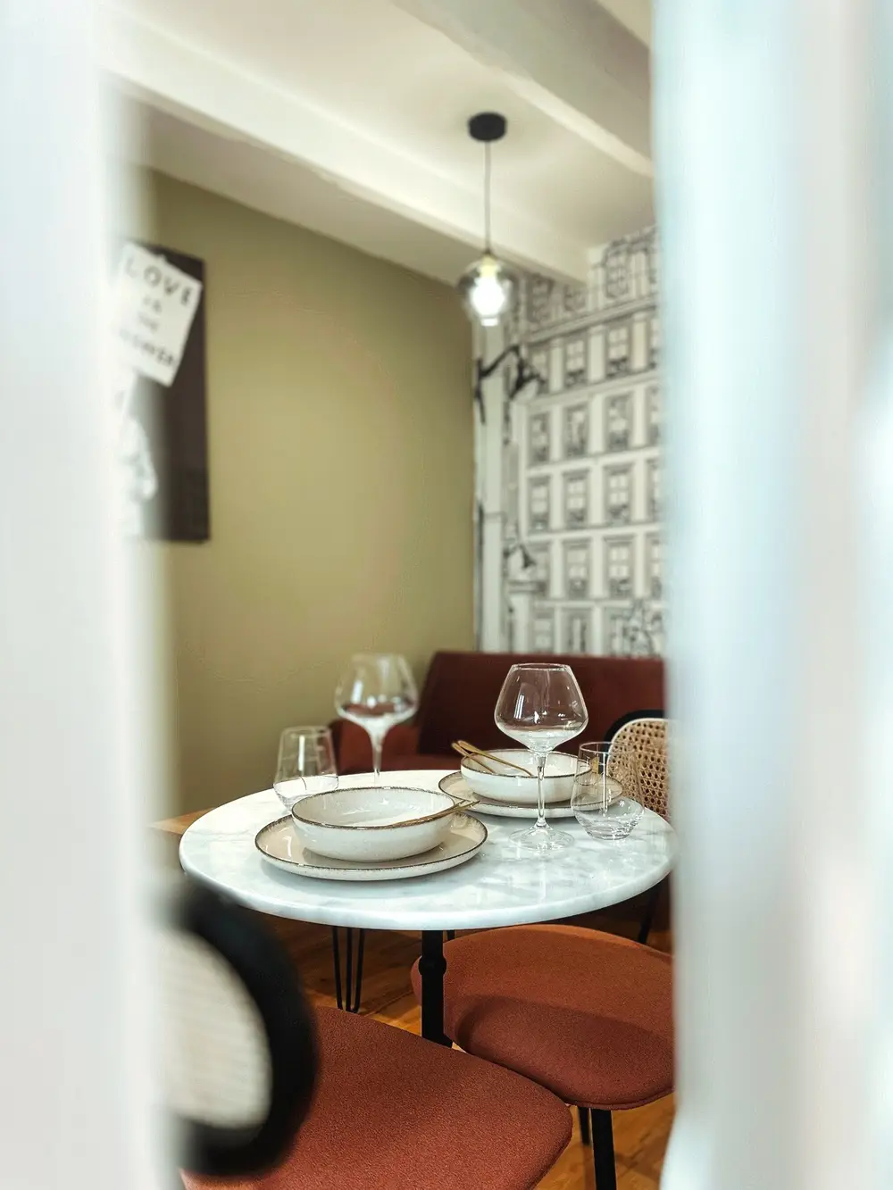 Table bistrot dressée dans un studio décoré d'un papier peint façon Paris