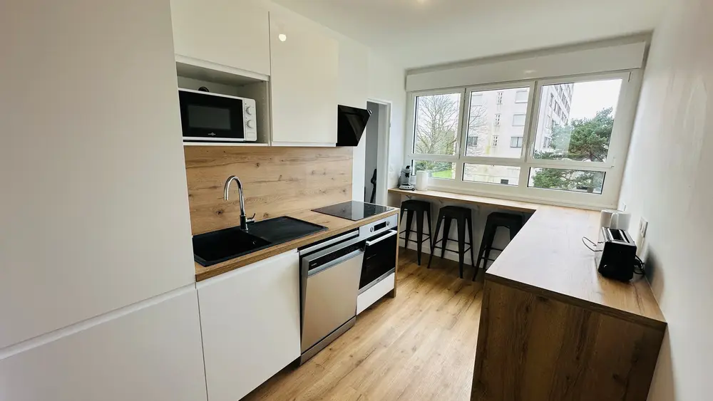 Cuisine équipée ouverte avec comptoir bar dans un appartement lumineux à Nantes