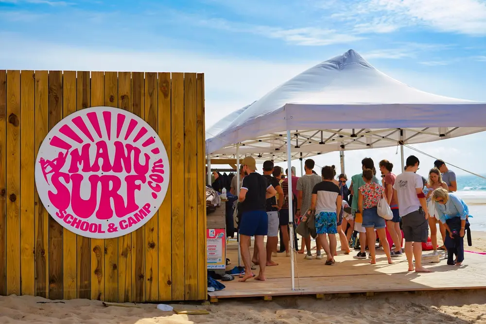 Stand d'une école de surf animé par un groupe de participants sur la plage