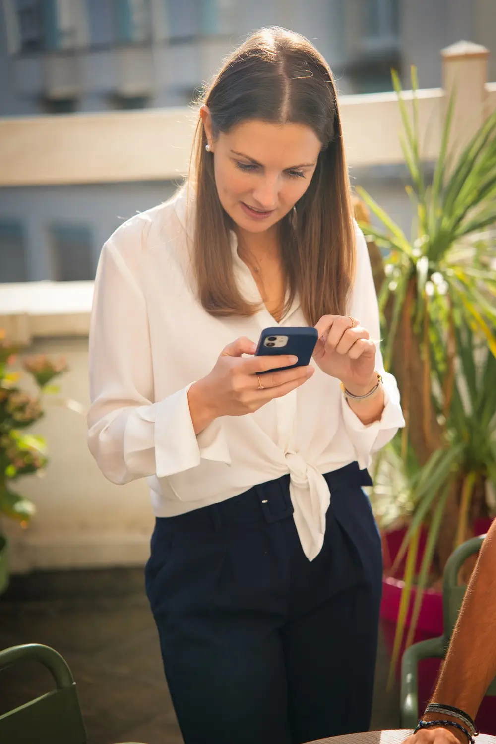 Une entrepreneuse consulte son smartphone sur une terrasse végétalisée à Nantes