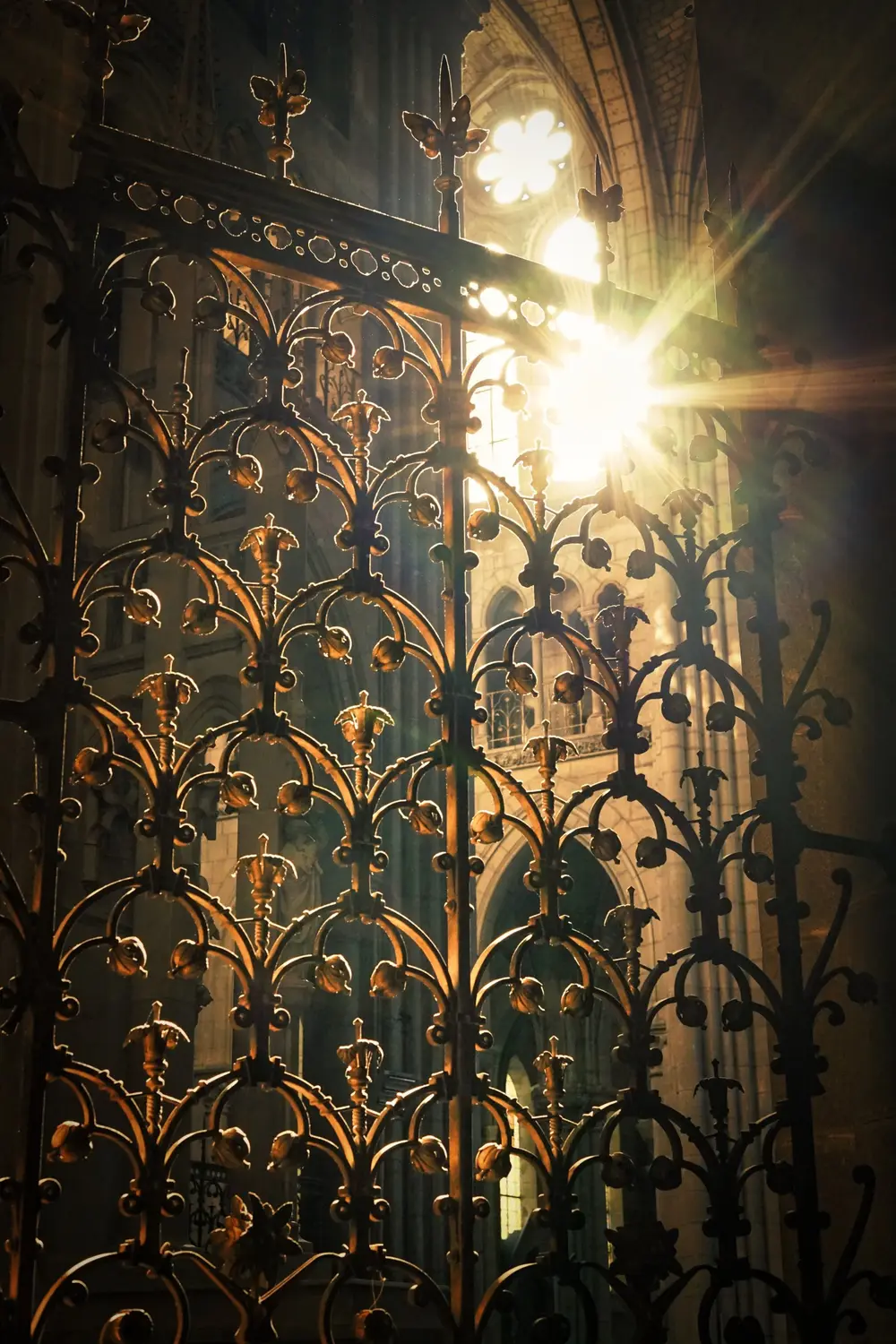 Grille en fer forgé d'une cathédrale traversée par un rayon de soleil