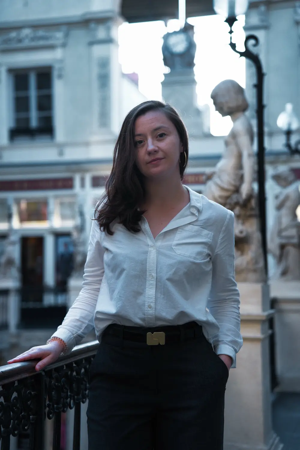 Notaire en chemise blanche appuyée à la rambarde, à côté d'une statue du passage Pommeraye