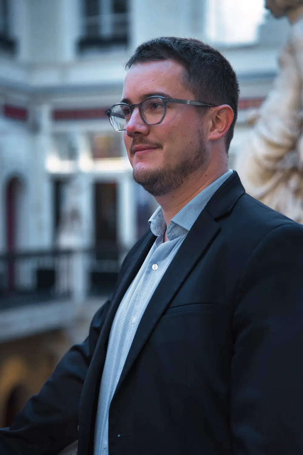 Portrait de profil d'un notaire souriant en veste sombre dans le passage Pommeraye