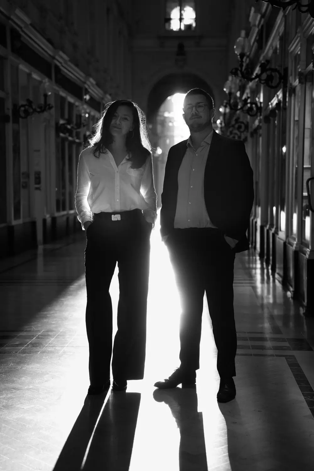 Portrait en noir et blanc des deux notaires associés de l'étude Houget et Boucard, à contre-jour dans le passage Pommeraye à Nantes