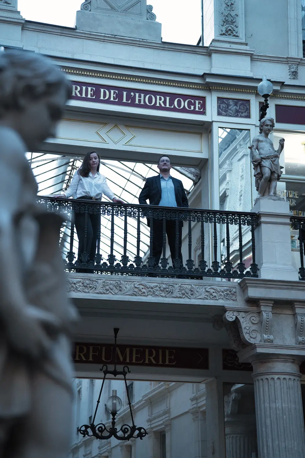 Les deux notaires au balcon de la galerie de l'Horloge, vus derrière une statue du passage Pommeraye
