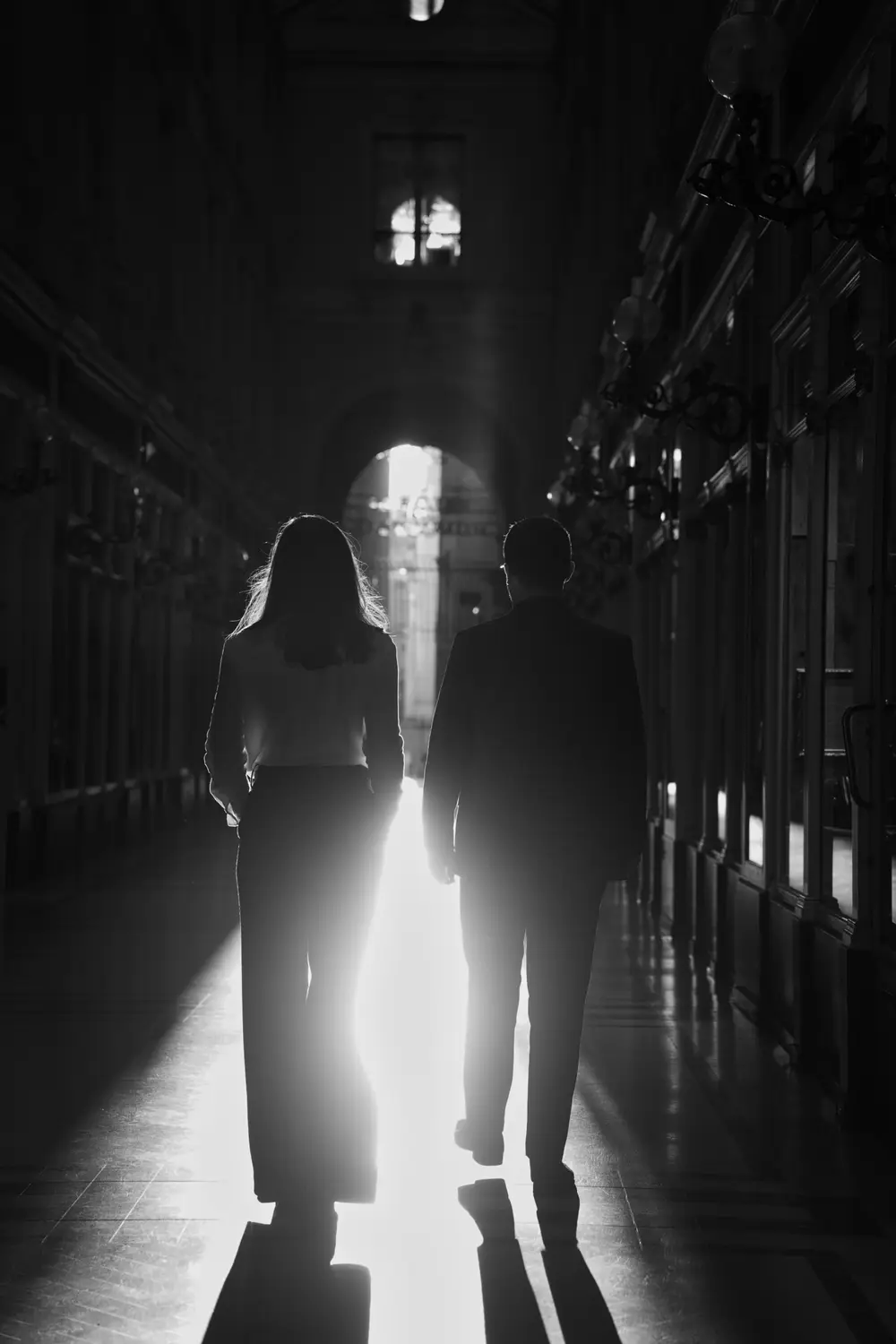 Les deux notaires de dos marchant vers la lumière dans le passage Pommeraye, en noir et blanc
