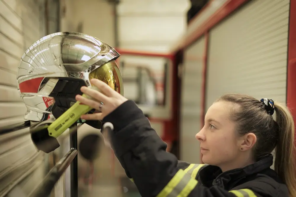 Portrait d'une sapeuse-pompière accrochant son casque dans une caserne