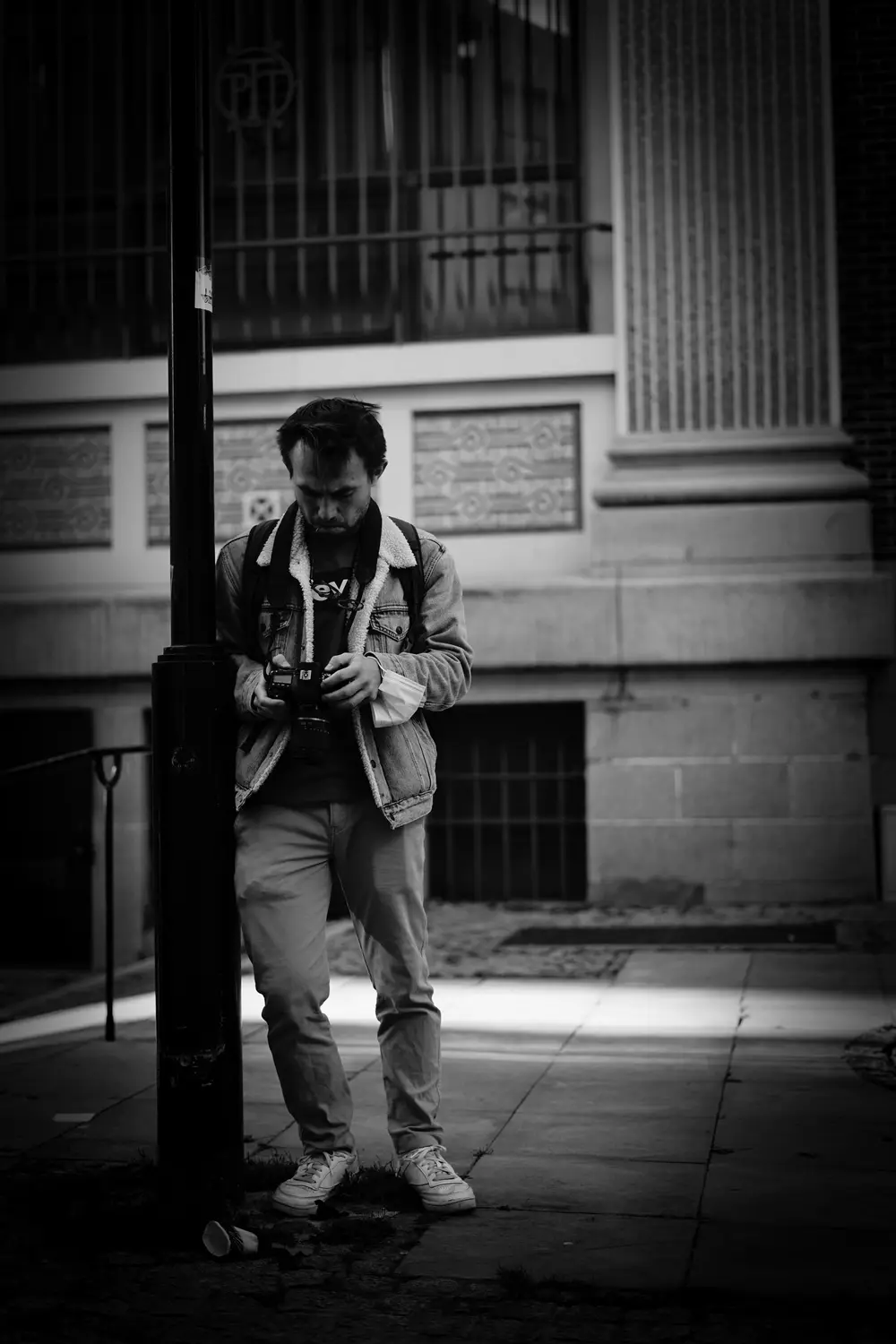 Portrait en noir et blanc d'un jeune homme réglant son appareil photo dans la rue