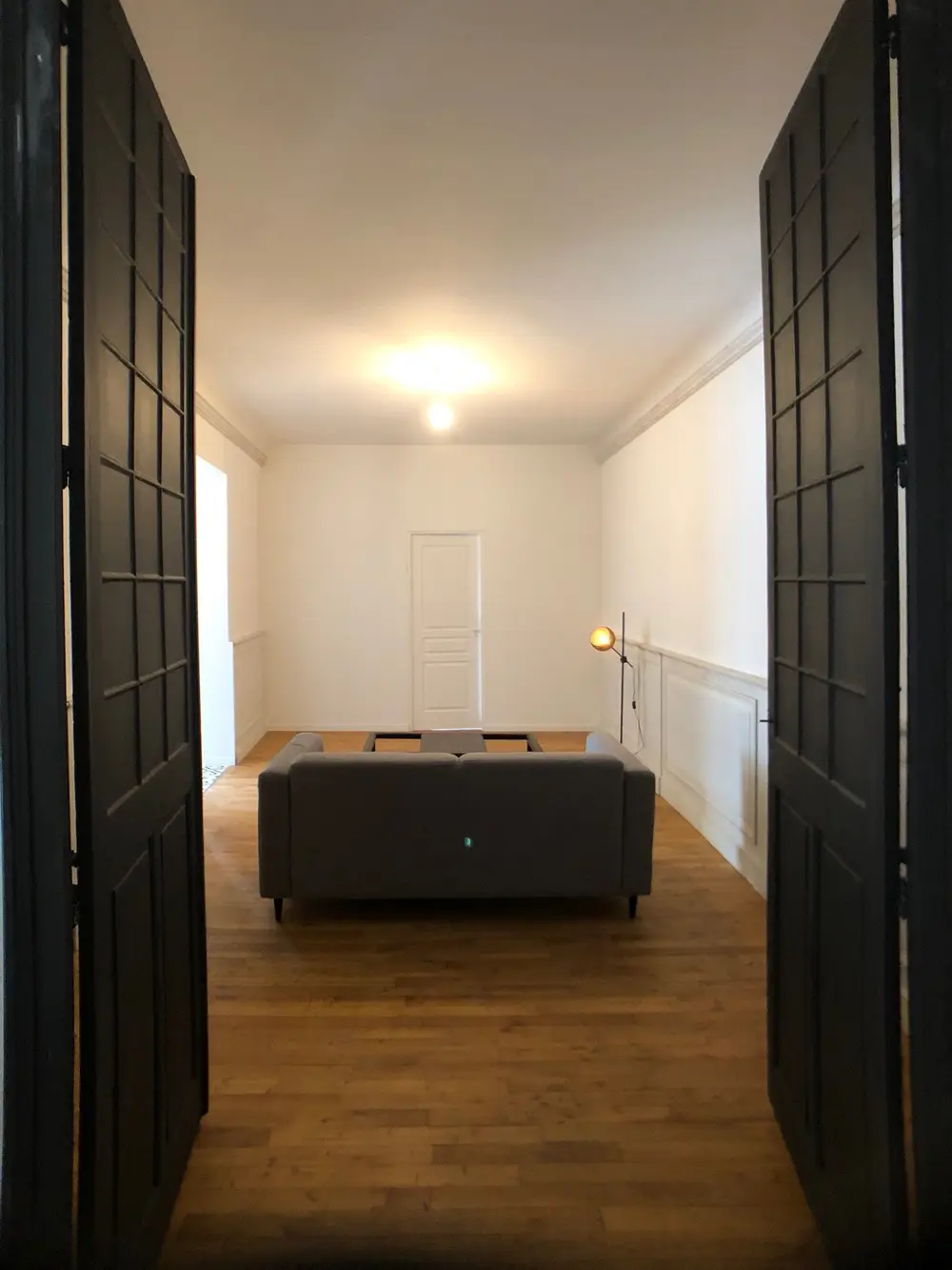 Double porte ouvrant sur le salon lumineux d'un appartement rénové à Nantes