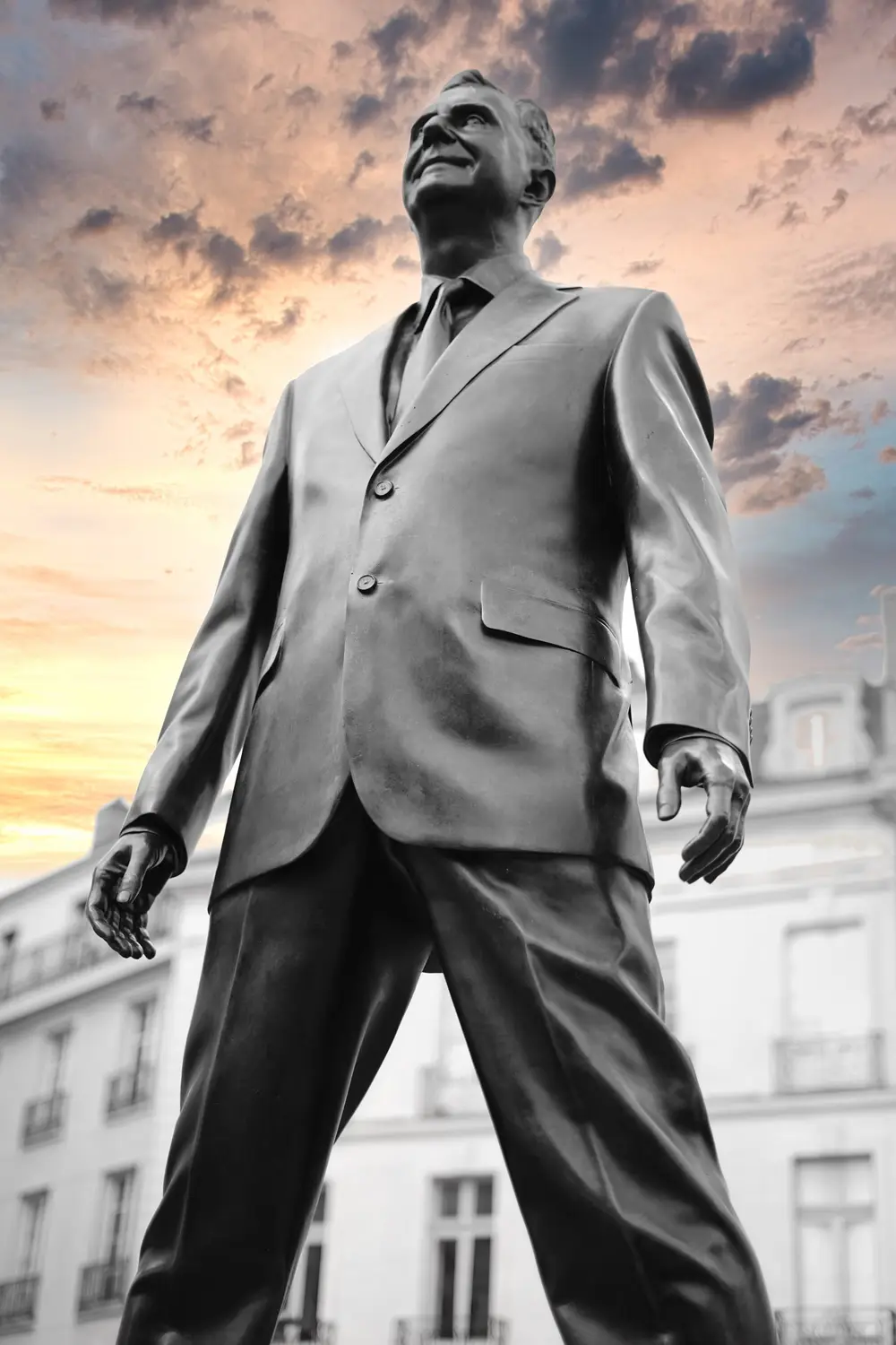 Statue d'un homme en costume photographiée en contre-plongée sous un ciel coloré